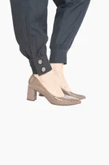 Zapato tipo stiletto con tacón de bloque, confeccionado en cuero charol con textura grabada efecto cocodrilo. Presenta una silueta clásica de salón con punta fina.
