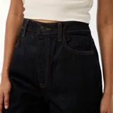 Jean de corte regular y tiro alto, confeccionado en denim azul oscuro. Presenta un diseño de pierna recta con un dobladillo ancho y llamativo en la parte inferior que deja ver el revés de la tela.