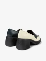 Mocasín de cuero color blanco con detalle de antifaz en negro y azul. Tiene suela track color negro y taco cuadrado.