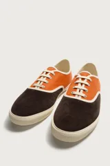 Zapatilla casual de hombre con diseño combinado en color naranja y marrón oscuro, con cordones y suela de goma en contraste.