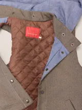 Chaleco con capucha, presenta una espalda de pelo sintético en color marrón oscuro con etiqueta de cuero negra y una capucha de tela tipo denim azul. Diseño original con mezcla de texturas.