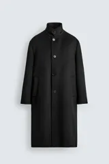 Abrigo negro de corte recto confeccionado en tejido con lana. Tiene cuello alto, manga larga con puños abotonados, bolsillos laterales y abertura en la espalda. Cierre frontal con botones.