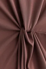 Top de manga larga color marrón, con escote redondo, hombros caídos y diseño entallado con detalle de nudo drapeado en la cintura.
