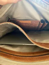 Bolso tote de cuero color marrón con doble asa de hombro y bolsillo externo con cierre.