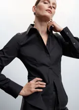 Camisa básica de algodón color negro, con cuello camisero, manga larga con puños abotonados y cierre frontal de botones.