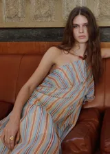Vestido largo con diseño halter, estampado de rayas verticales en tonos celestes, naranjas y blancos, con detalle de volantes en el escote y abalorios en el cuello.