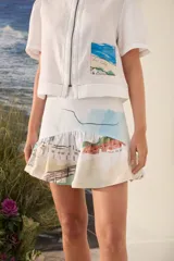 Falda corta de lino con estampado artístico de paisajes y volado inferior. Cuenta con cierre en la parte trasera.