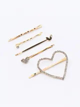 Set de cinco hebillas para el pelo en color dorado, que incluye tres horquillas simples con formas onduladas y dos hebillas con detalles de corazones decorados con cristales.
