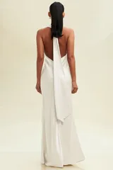 Vestido largo de satén color blanco, con diseño halter y escote drapeado tipo cowl neck. Presenta una silueta fluida y elegante con caída suave, ideal para eventos formales.