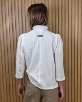 Camisa de algodón color blanco, con cuello alto con volados, mangas tres cuartos con detalles de bordado ingles y cierre frontal con botones de nácar.