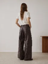 Pantalón de tiro alto confeccionado en cuero vacuno con textura croco. Presenta una silueta de pierna extra ancha, cierre frontal con botón y bolsillos laterales.