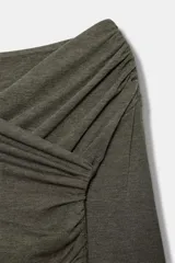 Top de manga larga con escote cruzado y detalle de tejido drapeado en el frente. Presenta un corte ajustado y bajo recto.