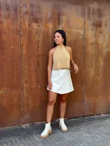 Falda corta tipo wrap de cuero color crudo, con diseño cruzado y ajuste mediante tiritas laterales.