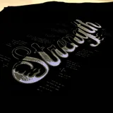 Remera negra de corte oversized con estampado en el centro de la espalda con la palabra "Strength" en tipografía cursiva con efecto de luces.