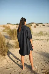 Vestido camisero corto de jean azul oscuro, con cuello clásico, mangas 3/4 con puños arremangados y cierre frontal con botones dorados.