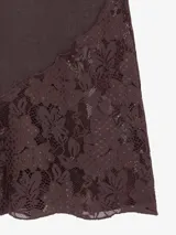 Bermuda holgada de lino color beige, con cintura elastizada y cordón de ajuste, pierna ancha por debajo de la rodilla y grandes recortes diagonales de encaje transparente en las pantorrillas.