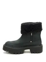 Bota de caña corta en color negro, confeccionada en nubuck con cuello de peluche sintético. Presenta una suela de plataforma dentada de goma, brindando un estilo robusto y moderno.