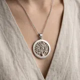 Dije circular de acero inoxidable con diseño calado de árbol de la vida.