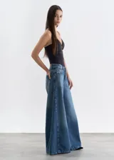 Jean de tiro medio con corte wide leg extra ancho, confeccionado en denim azul con efecto lavado y costuras laterales destacadas.