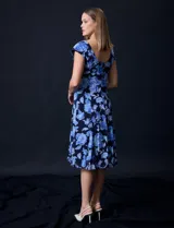 Vestido midi de gasa con estampado floral azul sobre fondo negro, torso drapeado y forro interno a tono.