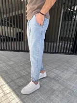 Pantalón jeans slouchy de hombre, en tono azul claro, con diseño de corte holgado en las piernas y botamangas ligeramente ajustadas o dobladas.
