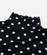 Blusa de cuello alto y manga larga, confeccionada en viscolycra con estampado de lunares blancos sobre fondo negro.