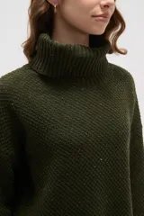 Polera de tejido de punto con cuello alto, diseño holgado y mangas largas. Presenta una textura de relieve tipo waffle en color natural.