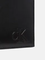 Billetera bifold de cuero negro con diseño compacto y monograma de Calvin Klein grabado en relieve en la parte frontal. Cuenta con múltiples ranuras para tarjetas y compartimento para billetes.