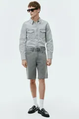 Bermuda de cinco bolsillos en denim de algodón grueso. Modelo de cintura estándar con cierre y botón, y piernas de corte relajado.