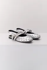 Balerina negra de cuero con punta fina y dos correas marrones con hebilla sobre el empeine. Decorada con tachas plateadas.