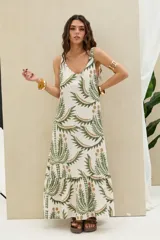 Vestido largo de tirantes en color blanco con estampado botánico en tonos verde y marrón, escote redondo y falda con volados en el ruedo.