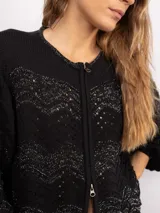 Campera de punto con cierre frontal bidireccional, mangas largas abullonadas y diseño calado con patrón de ondas en color negro con detalles brillantes.