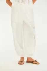 Pantalon ancho de lino y algodon color blanco, con bordado calado en los laterales, bolsillos y botamangas elastizadas.