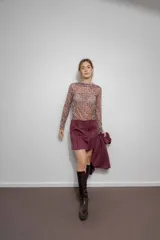 Falda corta de gamuza color bordó, con detalle de bordado geométrico vertical en el frente y bolsillo decorativo lateral.