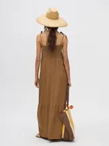 Vestido midi de denim color marrón, con corte holgado, breteles finos con lazos ajustables y detalle de volado en el ruedo.