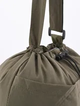 Bolso tipo tote de color beige, con diseño minimalista, cierre superior mediante cordón ajustable y costuras visibles en contraste.