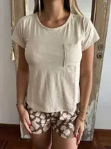 Conjunto de pijama compuesto por remera de manga corta color beige con bolsillo en el pecho y short estampado con manchas marrones.
