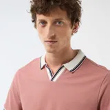 Remera polo de manga corta color rosado, con cuello y ribetes en las mangas de color blanco con líneas negras y azul marino. Presenta diseño con escote en V sin botones.