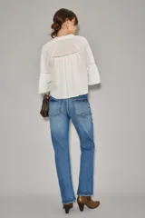 Jean de corte recto y tiro alto, confeccionado en denim azul con un lavado localizado que presenta efecto de bigotes y torceduras. Cuenta con cierre y botón frontal.