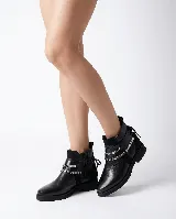 Bota corta tipo chelsea de cuero negro, con paneles laterales de gamuza y suela plana de goma. Presenta un diseño minimalista con tirador en la parte trasera.