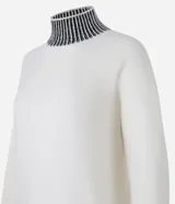 Suéter de punto pesado color blanco con cuello alto, puños y ruedo acanalados en contraste con rayas negras. Presenta diseño de hombros caídos y manga larga.