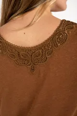 Remera color marrón con cuello redondo y detalle de encaje en el escote, de corte recto y manga corta.