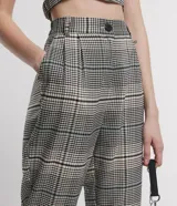 Pantalón zanahoria de sastrería con estampado de cuadros, bolsillos laterales, botón en la cintura y cierre por botón y cremallera.