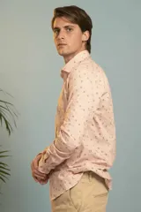 Camisa de manga larga en color salmón con estampado de pequeños motivos geométricos oscuros, cuello clásico y cierre frontal con botones.
