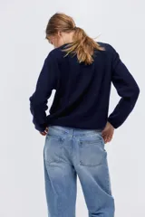 Saco de punto suave con lana, de corte holgado y diseño minimalista. Presenta cuello redondo, cierre frontal con botones y hombros levemente caídos. Posee terminaciones acanaladas en cuello, puños y bajo.