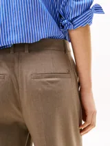 Pantalón de vestir color beige, de corte tobillero y pierna ancha. Confeccionado en tejido antiarrugas de mezcla de poliéster, viscosa y elastano. Presenta cierre de cremallera con enganche oculto, raya marcada en la parte delantera y trasera, y dos bolsillos traseros de ojal.