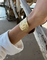 Brazalete rígido de diseño artesanal con textura irregular y acabado metálico, elaborado en bronce macizo.