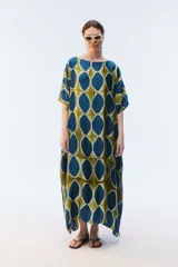 Kaftan maxi amplio de color amarillo, con escote redondo, mangas cortas y ruedo irregular. Presenta un diseño estampado a cuadros con efecto teñido.