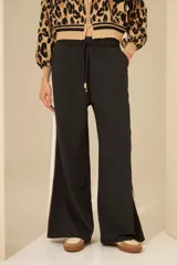 Pantalón negro de corte palazzo con cintura elástica y raya lateral blanca.