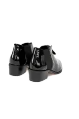 Botin de cuero negro con acabado charol y textura de reptil. Presenta cierre frontal con cremallera, paneles laterales elásticos y tacón bajo de bloque.